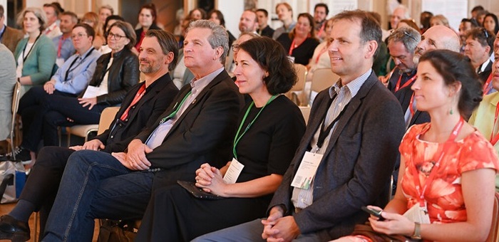 Men and women sitting in an conference audience and looking at the stage
